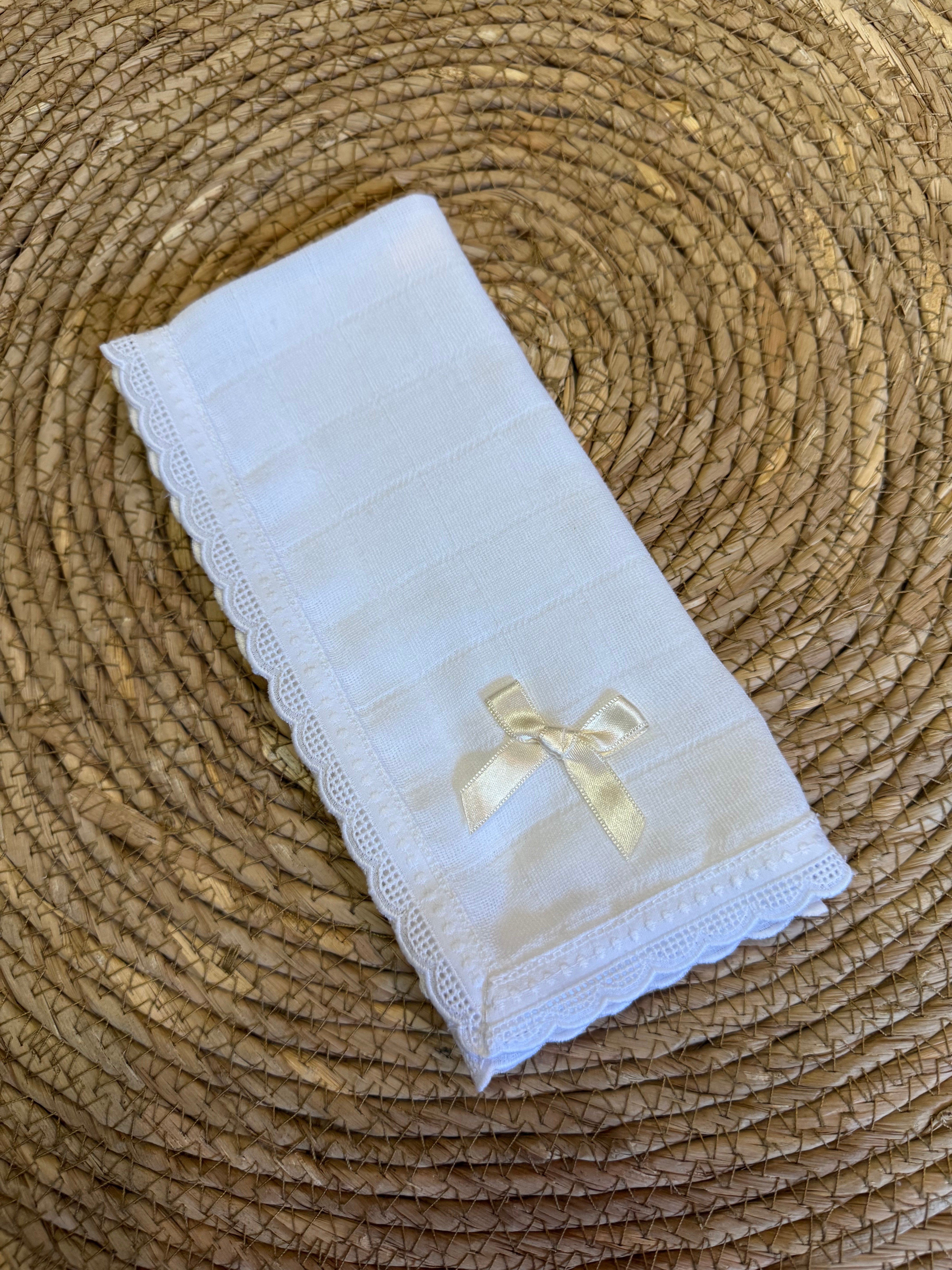 Mooi uitgewerkt spuugdoekje met kant en een satijnen strik in het creme.