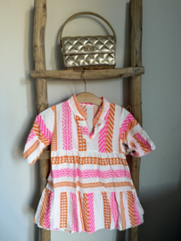 Vrolijk zomerjurkje in de kleuren fluor roze , oranje en wit .