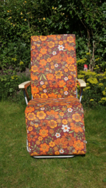 Vintage tuinstoel met benen omhoog, met retro bloemprint