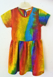 Vrolijk regenboogjurkje. Gemaakt van speciale BingBatik. Mouwtje met omslag en aangerimpelde rok. Sluit met knoopje achter. Maat 98/104 voor 3-4 jaar. 100% rayon, wasbaar op 30  graden.