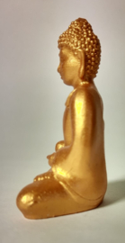 Goudkleurige boeddha zittend op een bedje van hematiet split. Op schitterend schaaltje van Balinees palisander.