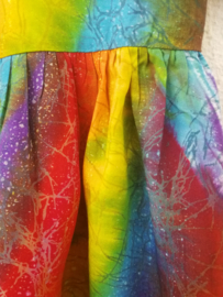 Vrolijk regenboogjurkje. Gemaakt van speciale BingBatik. Mouwtje met omslag en aangerimpelde rok. Sluit met knoopje achter. Maat 98/104 voor 3-4 jaar. 100% rayon, wasbaar op 30  graden.