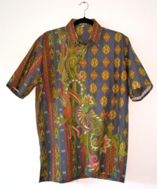 Authentieke Balinese batik blouse met korte mouw en  knoopsluiting. Wordt op de broek gedragen. Met zijsplitjes van 11 cm. Wijdte 110 cm. Lengte 71 cm. Schouderbreedte 51 cm. 100% katoen. Ned. maat 54.