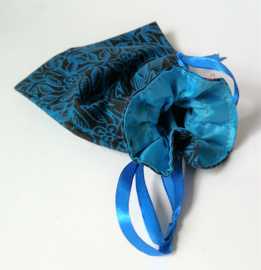 Turquoise/zwart batik offerzakje. Gevoerd met blauwkleurige satijn. Met blauw aantreklintje.