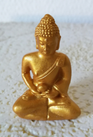 Goudkleurige boeddha zittend op een bedje van hematiet split. Op schitterend schaaltje van Balinees palisander. Schaaltje levering uit assorti.