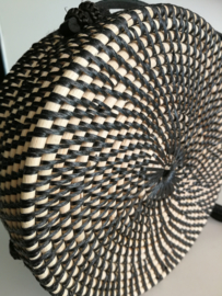 Meesterlijk vlechtwerk dit zwart wit opengewerkte rotan tasje.  Subliem afgewerkte sluiting en draagband van zwart leer. Lengte band 1.17 cm. Sluit met stevige drukknoop. Diameter 20 cm, 7 cm diep.