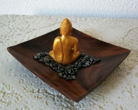 Goudkleurige boeddha zittend op een bedje van hematiet split. Op schitterend schaaltje van Balinees palisander. Schaaltje levering uit assorti.