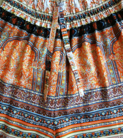 Broek '1001 nacht' abrikoos. Met breed elastiek in taille/ heupband, sierkoordje aan voorzijde, opgestikt zijvakje en elastiek in enkels. Binnenbeenlengte  75 cm. Heupwijdte tot 1.20 m, taille tot max 90 cm. 100% rayon.