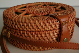 Meesterlijk vlechtwerk dit opengewerkte rotan tasje. Subliem afgewerkte sluiting en draagband van bruin leer. Lengte band 1.27 cm. Sluit met stevige drukknoop. Diameter 18 cm