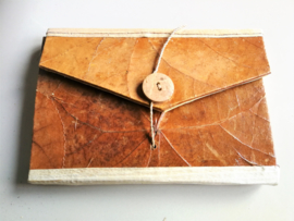 Eenvoudig handgemaakt notitie blokje van rijste papier. Enveloppe model. Sluit met koksnoot knoopje. 15x10 cm. Leverbaar uit assorti.