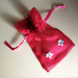 Handgemaakt cadeau zakje rood. Met opgenaaide Bali frangipani bloemetjes.