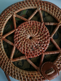 Meesterlijk vlechtwerk dit opengewerkte rotan tasje. Subliem afgewerkte sluiting en draagband van bruin leer. Lengte band 1.27 cm. Sluit met stevige drukknoop. Diameter 18 cm