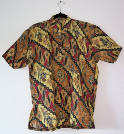 Authentieke Balinese batik blouse met korte mouw en mandarijnen boord. Wordt op de broek gedragen. Met zijsplitjes van 11 cm. Wijdte 112 cm. Lengte 65 cm. Schouderbreedte 48 cm. 100% katoen. Ned. maat 54.
