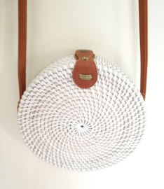 Wit rotan tasje. Subliem afgewerkte sluiting en draagband van bruin leer. Lengte band 1.26 cm. Sluit met stevige drukknoop. Diameter 20 cm 6,5 cm diep.