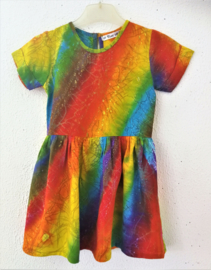 Vrolijk regenboogjurkje. Gemaakt van speciale BingBatik. Mouwtje met omslag en aangerimpelde rok. Sluit met knoopje achter. Maat 98/104 voor 3-4 jaar. 100% rayon, wasbaar op 30  graden.