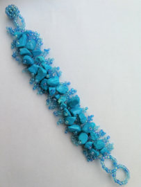 Fluor blauwe armband met ingelegde steentjes. 2,5 x 18 cm.