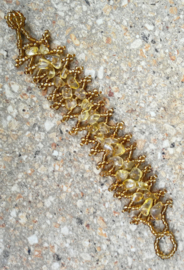Goudkleurige armband met ingelegde steentjes.