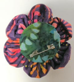 Prachtige bloem corsage/broche van batik stof met kokos knoopje. Diameter 7 cm.