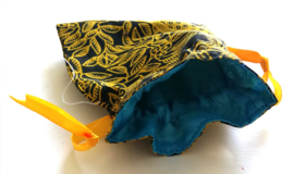 Zwart goud batik offerzakje. Gevoerd met lichtblauw kleurige satijn. Met goud aantreklintje.  Printjes kunnen verschillen.