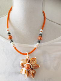 Artistieke ketting in oranje pasteltinten. Gemaakt van rond geslepen parelmoer schelpjes. Nikkelvrije sluiting. Lengte 56 cm.