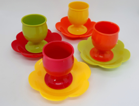 Vier gekleurde, retro eierdopjes met schoteltje
