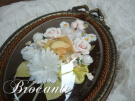 Vintage kader met strik en bloemen onder gebombeerd glas