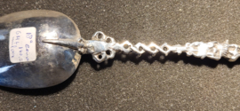 De zilveren lepel heeft een gedeeltelijk bewerkte en getorste steel, waarop aan het einde de vrouw met het anker en de duif.- De Hoop