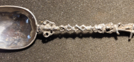 De zilveren lepel heeft een gedeeltelijk bewerkte en getorste steel, waarop aan het einde de vrouw met het anker en de duif.- De Hoop