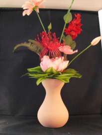 Zijde bloemen in een zalmkleurig bolvaasje, roze-rood