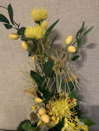 Oker/gele tulpvormige cachepot gevuld met geel/groene tinten