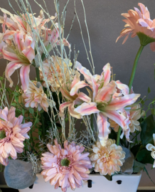 Witte vaas met stokjes met roze, zalme en grijze tinten