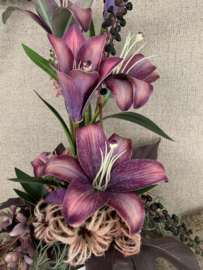 Bloemstuk in ruwe grijze pot met mauve lelie's, paarse bessen, roze clematis, mauve wisteria met goud, bruin/paars blad, grijze tillandsia