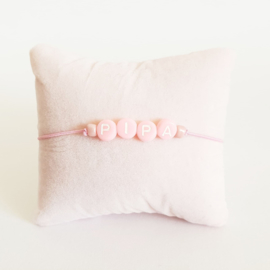 Armbandje roze elastiek + roze kraal met witte letter + licht roze rocaille