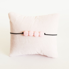 Armbandje zwart elastiek + roze kraal met witte letter
